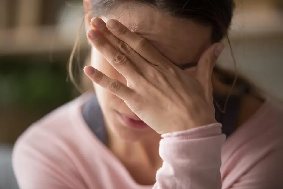 A worried parent with her head in her hand