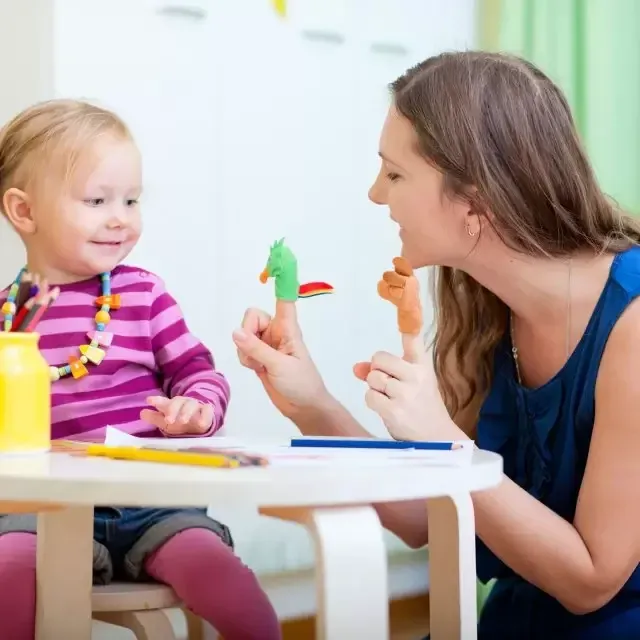 A parent using finger puppets with her toddler